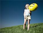 Jeune fille sur une colline en tenant le ballon happy face