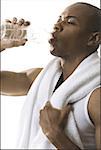 Close-up of a young man drinking water from a bottle