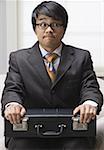 Close-up of a businessman sitting and holding a briefcase