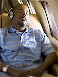 A man listening to music on headphones in an airplane
