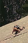High angle view of a young woman climbing on a rock