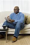 Senior man sitting on a couch and reading a newspaper