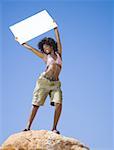 Low angle view of a young woman holding a blank sign