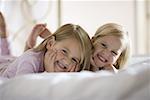 Portrait of two sisters lying on the bed