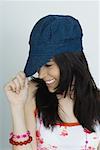 Teenage girl pulling cap down, smiling, portrait