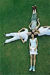 Group of young friends lying on grass with heads together