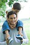 Boy riding on father's shoulders, both smiling