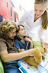 Boy and girl playing doctor, nurse looking over their shoulders