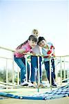 Children on playground equipment, smiling at camera