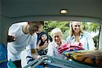 Family unloading beach material out of trunk of car
