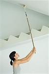Woman painting ceiling with paint roller