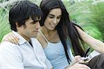 Young couple outdoors together, looking at cell phone