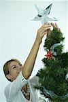 Woman putting star on top of Christmas tree