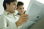 Father and son reading newspaper together