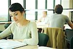 Female college student sitting at table in library, studying