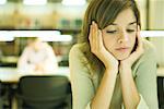 Female college student sitting at table in library, studying