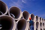 Construction Worker Standing in Front of Concrete Pipes