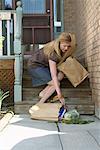 Woman Picking up Groceries from Front Steps of House