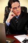 Young businessman sitting at desk and thinking