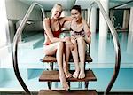 Two young woman  sitting next  to spa pool