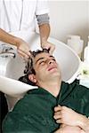 Jeune homme ayant ses cheveux lavé dans un salon