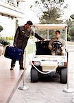Bellboy driving hotel cart to deliver luggage to doorman