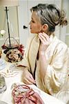 Woman sitting at the dressing table and putting in ear ring