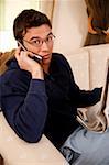 Young man reading newspaper and talking on cell phone