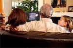 Mature couple watching television with young girl