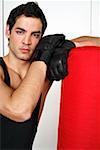 Young man leaning on punching bag