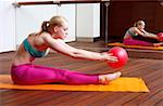 Young woman performing a pilates stretch with a ball