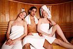 Man with two young women enjoying a sauna