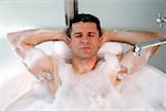 Man relaxing in bathtub with bubbles