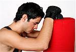 Young man leaning on punching bag