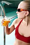 Jeune femme à boire du jus à la piscine thermale