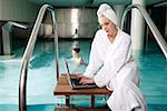 Woman on computer next  to a swimming pool