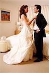Bride undressing groom in hotel room