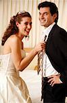 Bride pulling groom's tie off in hotel room