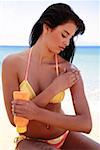 Jeune femme en bikini, appliquer la lotion solaire
