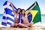 Young women on beach holding up flags