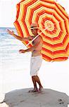 Man marching on beach with beach umbrella