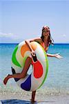 Young woman on beach with inflatable life ring