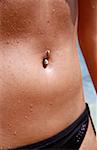 Belly of young woman on beach with belly button ring