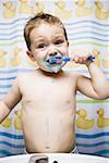 Young boy brushing teeth in bathroom sink