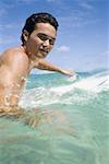 Man in water with surfboard smiling