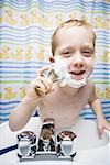 Boy shaving in bathroom and smiling