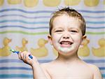 Boy with toothbrush in bathroom smiling