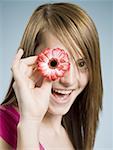 Close-up of woman smiling holding flower up to her eye