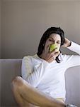 Woman sitting on sofa eating green apple