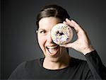 Woman holding donut up to eye and smiling